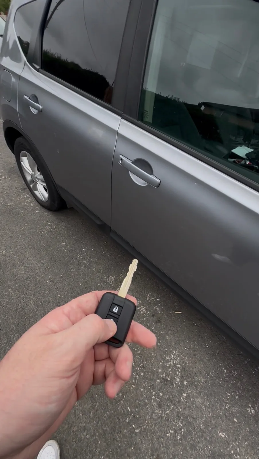Replacement remote key held at the door of a silver car in Derby