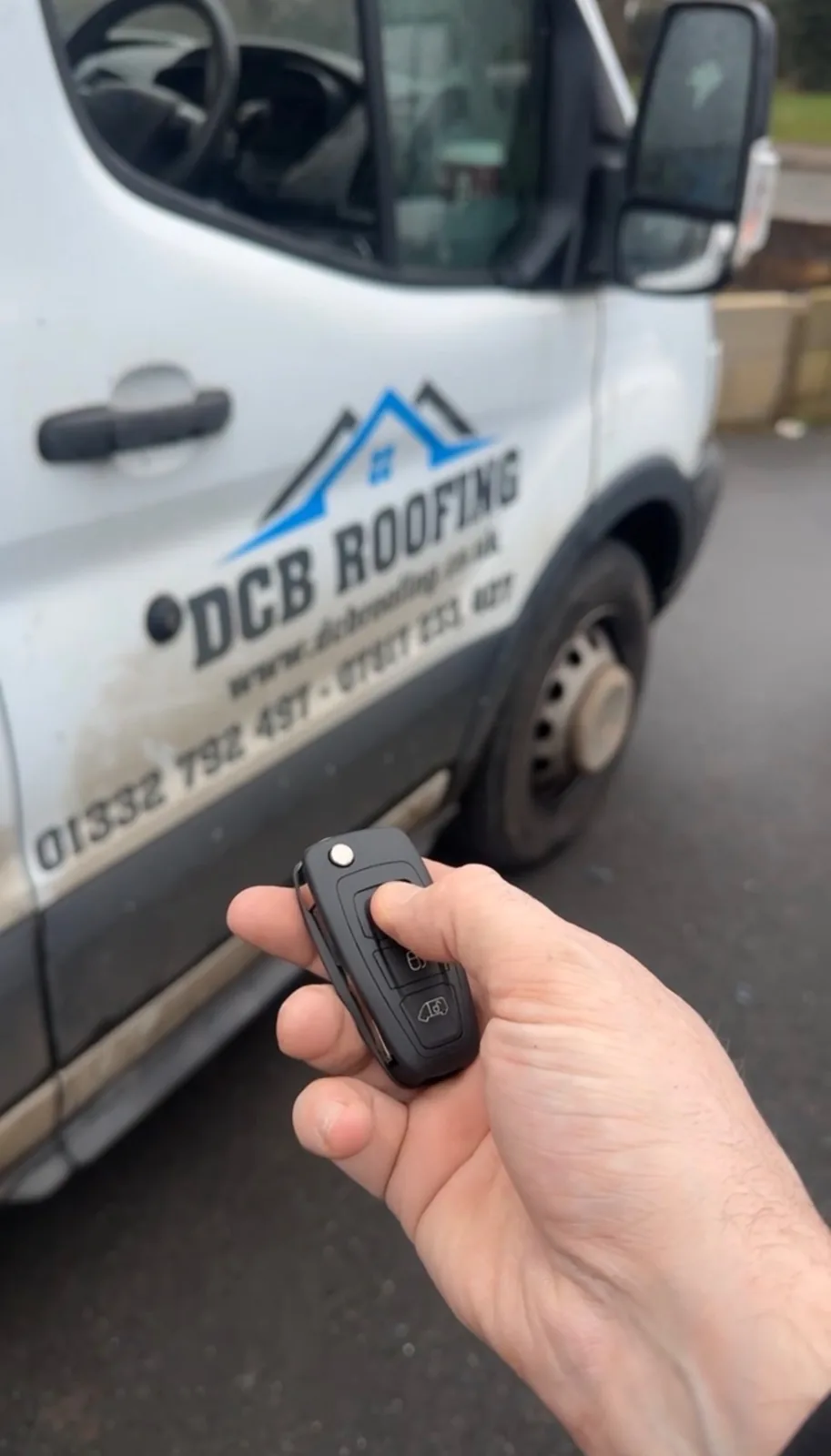 Replacement van key held in front of a DCB Roofing work van in Derby