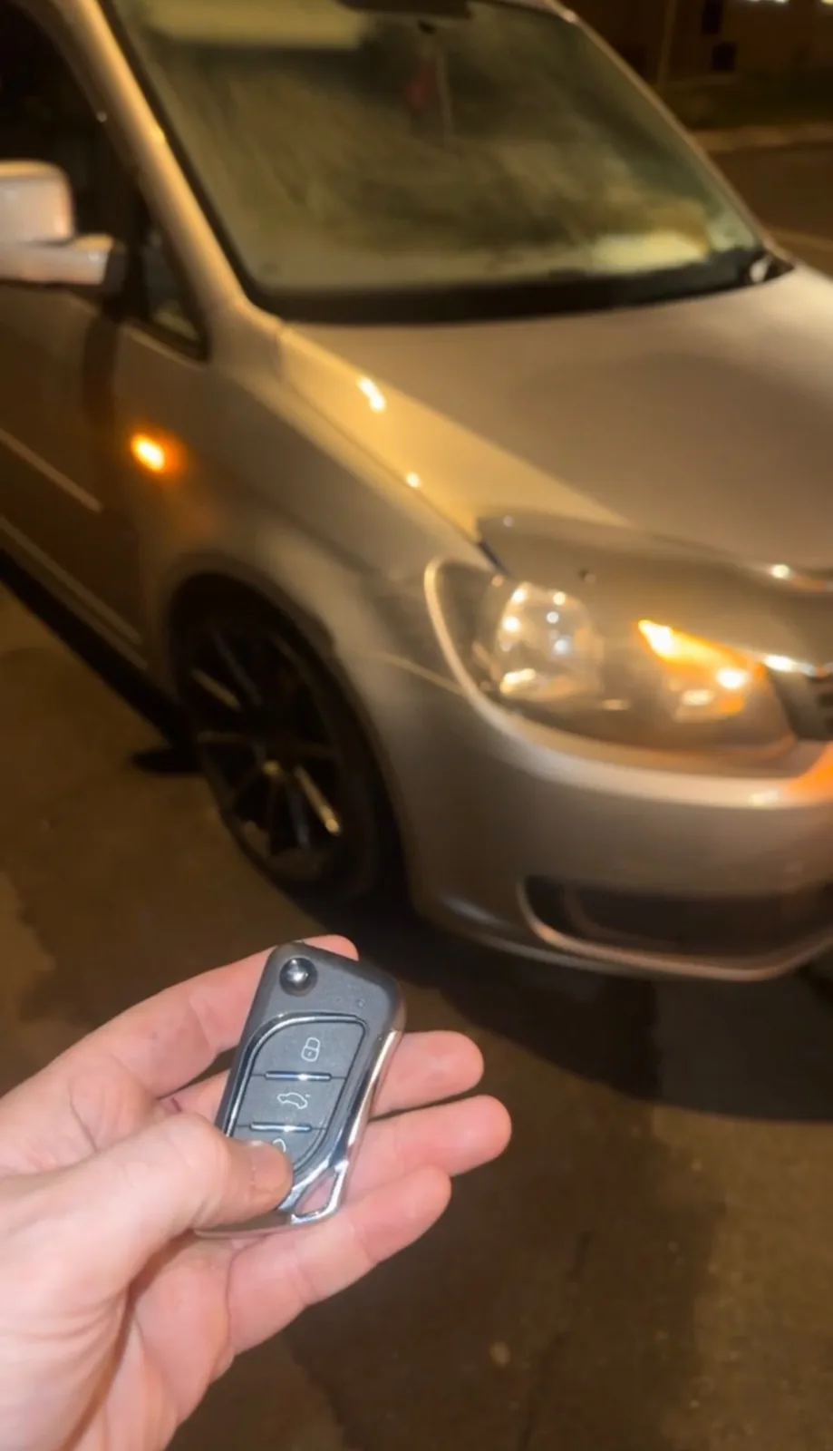 Volkswagen flip key held in front of a gold Volkswagen in Derby