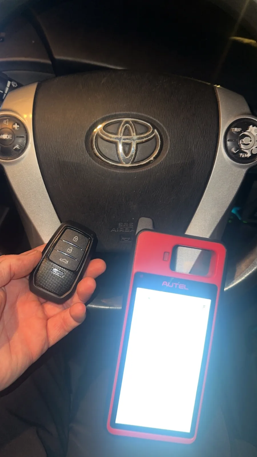 Toyota smart key being coded with a key programmer at the steering wheel