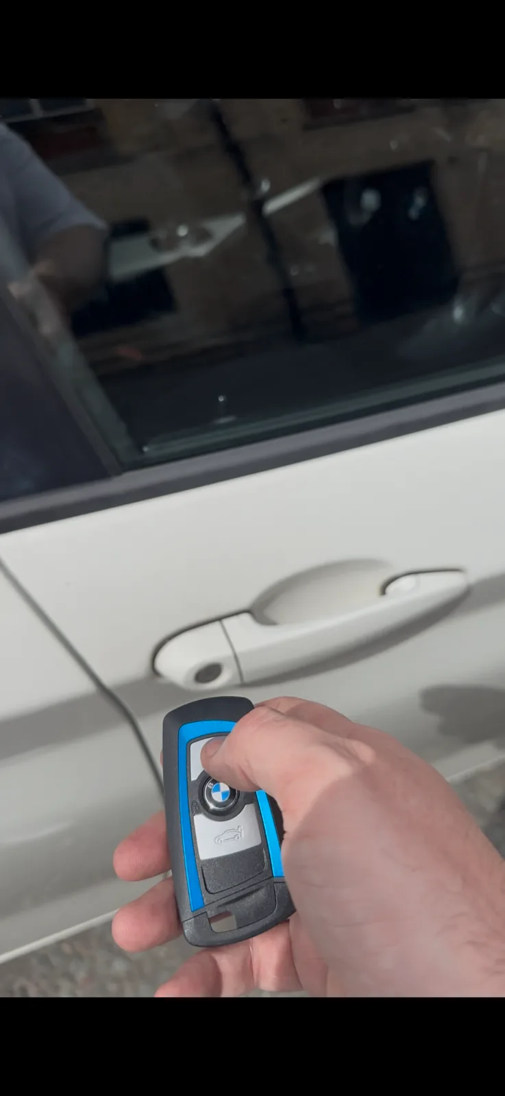 Blue BMW protective key held beside a locked BMW door for a spare key job